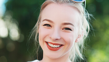 young woman smiling with braces outside